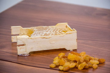 honey in honeycomb next to raisins on a wooden background