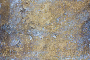 old concrete yellow ragged wall with blue spots of paint, damage and scratches. rough surface texture
