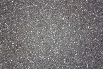 old gray asphalt with protruding multi-colored white and blue small stones. rough surface texture
