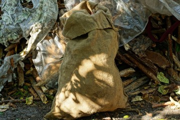 one full brown burlap bag on the street against the wall