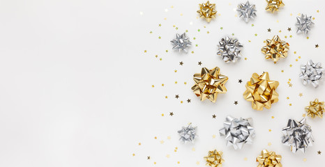 Christmas or New Year composition with gold and silver sparkling ribbon decorations on white background. Flat lay, copy space.
