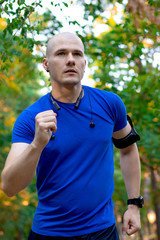 Young man athlete running  in the park. Autumn forest leaves. Caucasian male fitness concept.