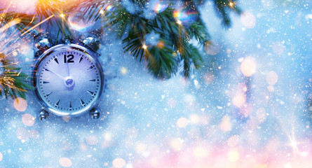 Fototapeta na wymiar Christmas and New Year holidays background with clock. Glitter lights backdrop. Winter season. Text space. Closeup of Christmas-tree branch.