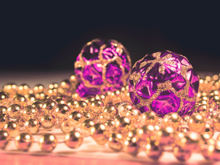 Christmas toys with the beads on the table a black background. Gold beads with purple balls....