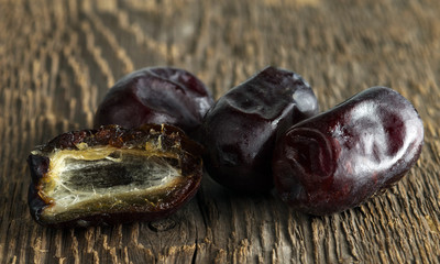 Three dates and a half on a wooden texture background.