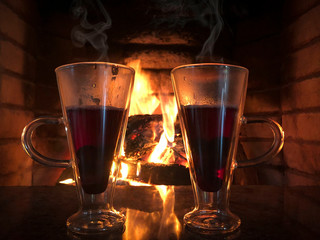 two glass of hot wines against a fireplace
