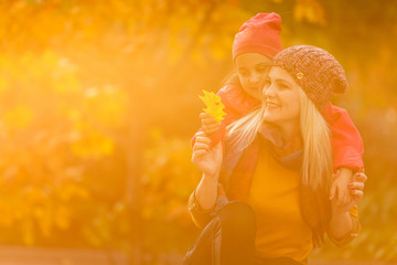 Mother giving daughter piggyback ride in autumn woodland