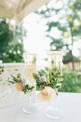 Two glasses with champagne for the bride and groom. Wedding decor from fresh flowers.