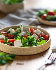 Greek salad on a light plate of cherry, Greek white cheese, green salad, with blurred background