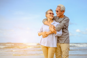 Fototapeta na wymiar Senior couples embrace on the beach at sunny day, plan life insurance with the concept of happy retirement.