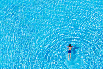 Top view of a child swimming in an outdoor pool.