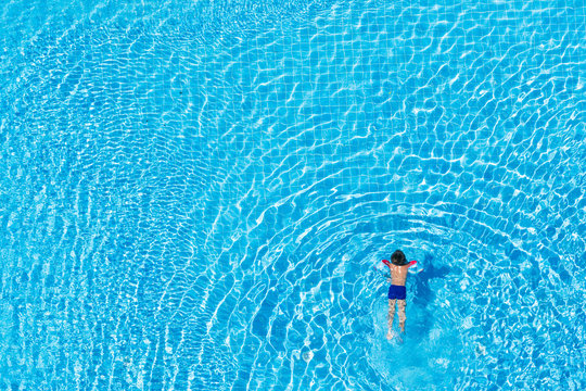 Top view of a child swimming in an outdoor pool.