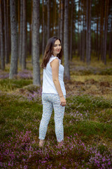 a photo of woman in the forest where the purple heather blooms. copy space. authentic image.