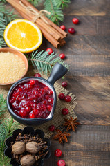 Cranberry sauce with ingredients on a wooden background.