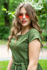 Portrait of young girl wearing green dress and red sunglasses. Close up. Plus size model.