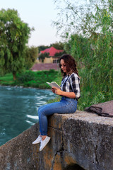 girl reading a notebook by the river on a concrete pier