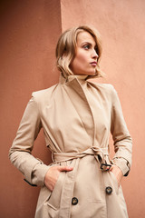 Side view of serious casual blond girl in trench coat confidently looking away outdoor