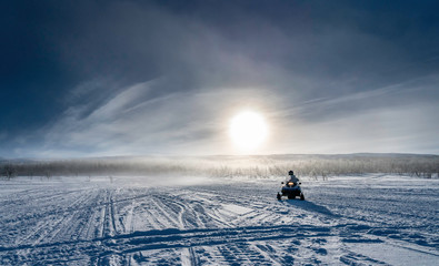 One person drives snowmobile in very cold mountains in Sweden, frosty fog around bright sun creates...