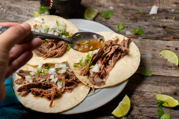 Mexican slow cooked lamb tacos also called barbacoa on wooden background