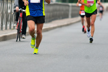 Fototapeta na wymiar Legs of runners Marathon race on the city road. Runners and cyclist