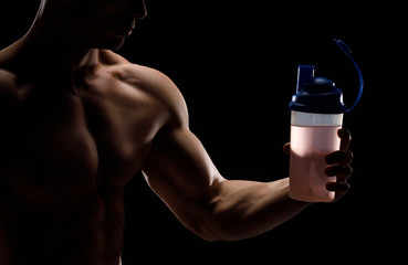 Model sports young man on dark background. Portrait of sporty strong muscle guy with protein drink in shaker. Sexy torso. Bodybuilding nutrition supplements, sport, workout, healthy lifestyle concept.