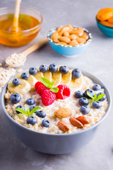 Oatmeal with berries and nuts for breakfast. Oatmeal with fruits, nuts and honey. Oatmeal with blueberries, banana and raspberries. Healthy food