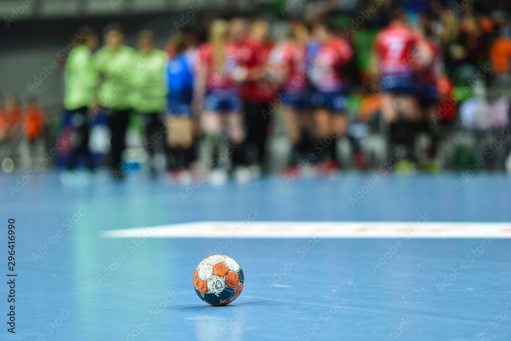 Wall mural handball ball lying on the blue parquet .