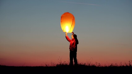 Little child hold lightning lantern release it on sunset sky, happy kid