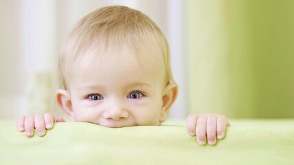 Happy baby portrait in crib, smiling face, child climbing with hands