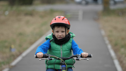 Obraz premium Little boy riding bicycle on alley, kid with protection helmet learning