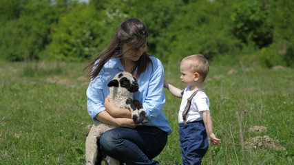 Fototapeta premium Baby child and mother portrait, parent holding little lamb, learn to love animal
