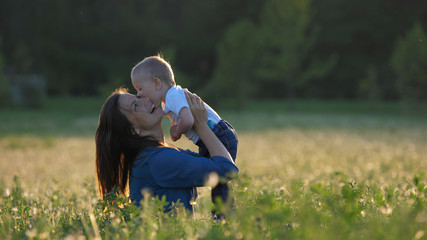 Naklejka na ściany i meble Mother hold baby and lift up in beautiful dandelion field, parent kiss child