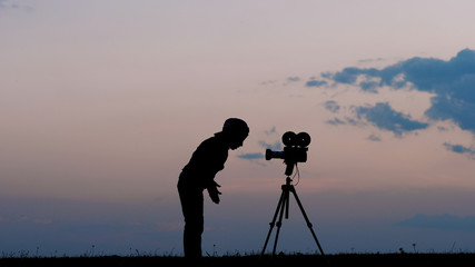 Funny kid playing role in front of photo video camera outdoor at sunset
