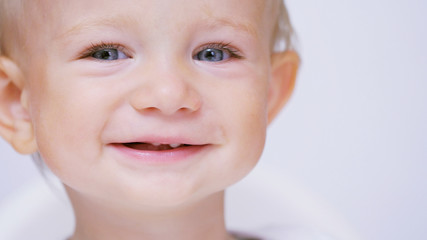 Happy baby with blue eyes smiling, child is shaking and coughing