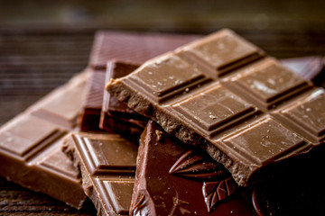black and milk chocolate pieces wooden table background