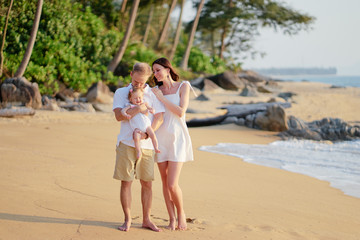 Family holiday near the sea. Father, mother and little daughter on beach.