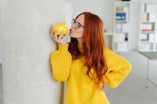 Young woman kissing her piggy bank