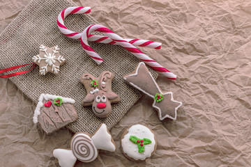 Christmas gingerbread cookies and candies on a burlap napkin on baking paper, Christmas concept, top view, flat lay