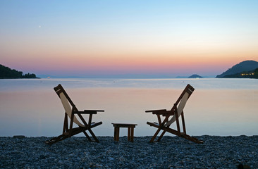 Empty sunbed chairs and table lounge private beach sunset