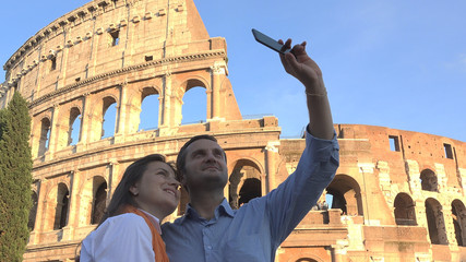 Couple taking a selfie to Colosseum, tavel in in Rome, beautiful blue serene sky