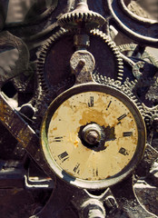ancient rusty iron clock with weathered face and exposed complex mechanism with cogs and gears