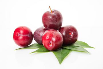 plums with plum leaves on a white background