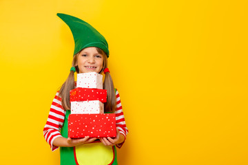Child in elf costume holding Christmas presents