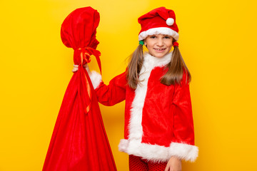 Little girl wearing Santa costume carrying presents