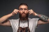 Stylish tattooed hairdresser grimacing at camera touching face