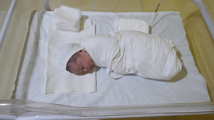 Swaddle new born baby sleep in child bed in hospital