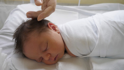 Close up to newborn baby sleeping, mother hand caress child head