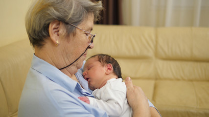 Sweet newborn baby child sleeping in grandmother arms, dreams in parent embrace
