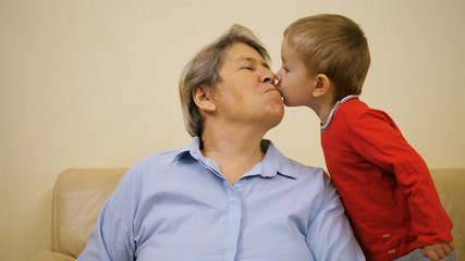 Lovely little child kissing grandma, happy moment indoor
