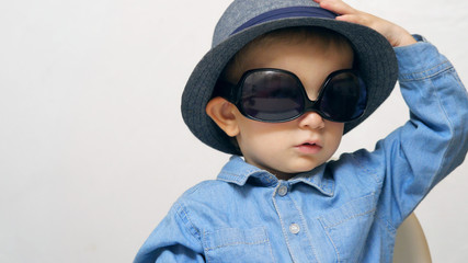 Funny child with blue yes arrange and taking off sunglasses and hat